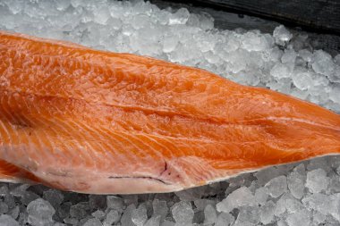 Ezilmiş buz üzerinde çiğ somon filetosu ahşap yüzeyde uzanıyordu.