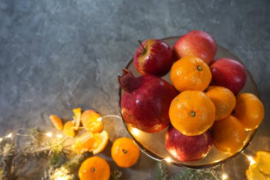 Gri arkaplanda noel süslemeleri ve meyveleri olan kompozisyon.