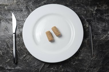  Beyaz tabakta iki şarap mantarı, masada çatal ve bıçak.