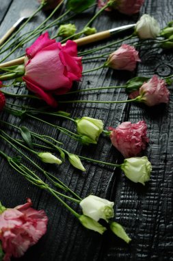 Güzel Eustoma çiçekleri ve siyah ahşap arka planda boya fırçaları.