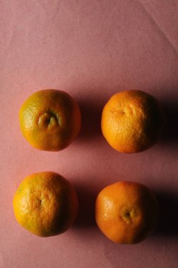 Pembe arkaplanda dört portakal, üst görünüm 