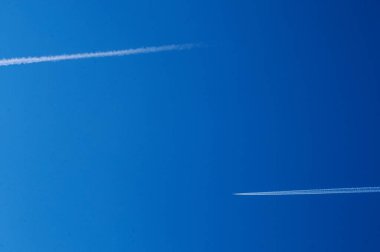 Beyaz çizgili mavi bir gökyüzü üzerinde iki uçak