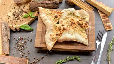 Masadaki tahtanın üzerinde baharatlı pide ekmeği. 