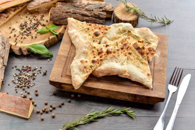 Masadaki tahtanın üzerinde baharatlı pide ekmeği. 