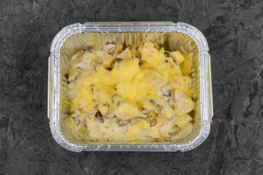 Kremalı sosta pişmiş tavuk ve mantarla servis edilen, folyo kabında servis edilen bir servis tabağı..