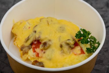 Kağıt kasede servis edilen peynir, mantar ve biberli omlet..