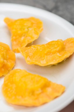 Beyaz bir tabakta servis edilen, kıtır kıtır soslu birkaç kızarmış hamur köftesi..