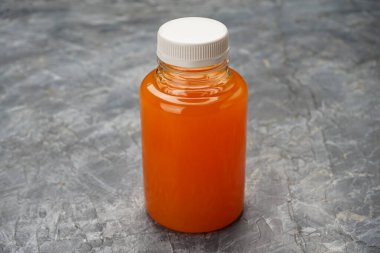 Beyaz kapaklı ve turuncu sıvılı plastik şişeyi temizle..