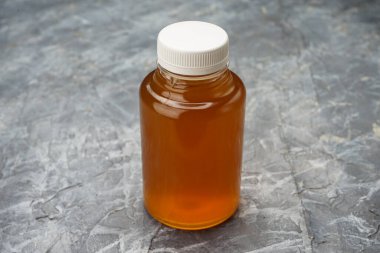 Beyaz kapaklı ve kahverengi sıvılı plastik şişeyi temizle..