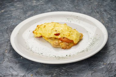 Eritilmiş peynirli tavuk filetosu ve domates dilimi..