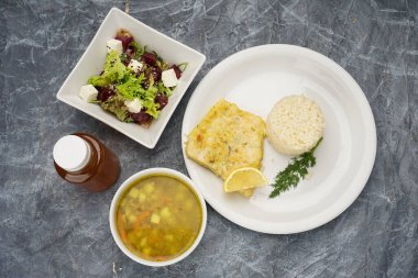 Balık, pilav, çorba, salata ve içecek ile dolu tam menü..