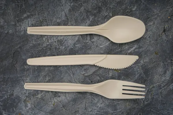 Çatal, bıçak ve kaşık dahil bej plastik çatal takımı..