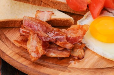 Domuz pastırması, kızarmış yumurta, tost ve domatesli kahvaltı tabağı..