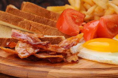 Domuz pastırması, kızarmış yumurta, tost ve domatesli kahvaltı tabağı..