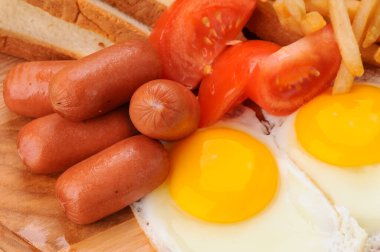 İki sahanda yumurta, sosis, patates kızartması ve domatesli doyurucu bir kahvaltı..