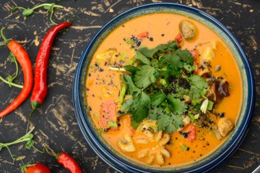 Canlı bir kase baharatlı çorba, tavuk, mantar ve bitkilerle..