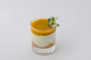 Bir bardak katmanlı tatlı, üzerine meyve püresi ve bir tutam nane..