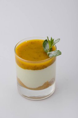 Bir bardak katmanlı tatlı, üzerine meyve püresi ve bir tutam nane..