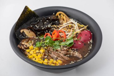 Etli, mısırlı, yumurtalı, mantarlı ve diğer sebzeli bir kase ramen..