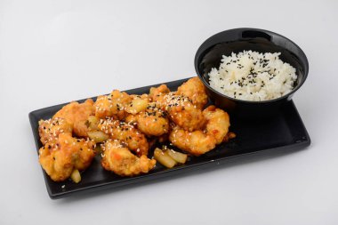 Kızarmış karnabahar ve pirinç, susam tohumları ve taze otlarla süslenmiş bir gurme..