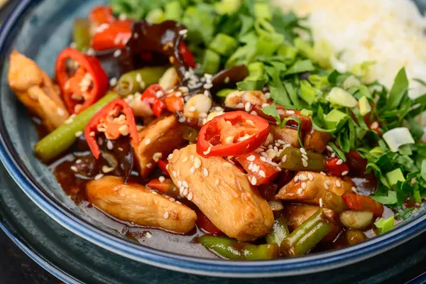 Tavuklu, sebzeli, biberli ve pirinçli kızarmış bir tabak..