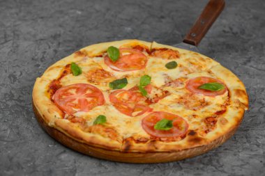 Tahta tahtada servis edilen domates ve fesleğenli taze margherita pizzası..