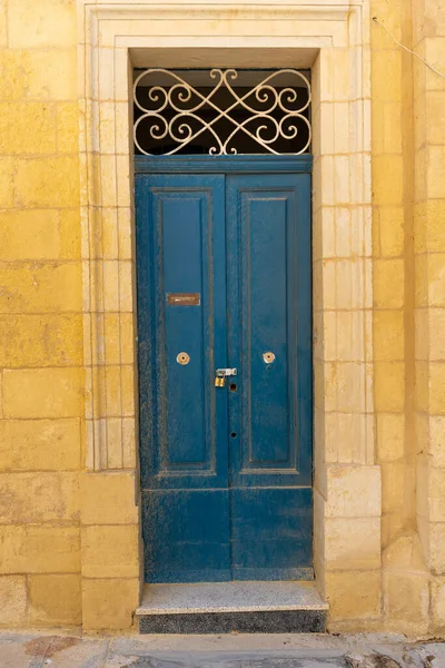 Dark blue door on an exterior brick wall. The building is somewhere in Malta.