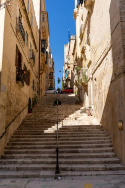 Valletta, Malta - 3 Kasım 2022: Malta adasındaki eski Valletta kasabasında merdivenleri olan tipik dar taş sokak