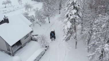 Mavi traktör karları temizliyor.