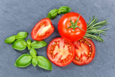 Tomatoes tomatos vegetables with basil from above on a slate from above