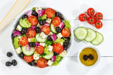 Taze domatesli Yunan salatası ve beyaz peynir tahta üzerinde sağlıklı yiyecekler yiyorlar.