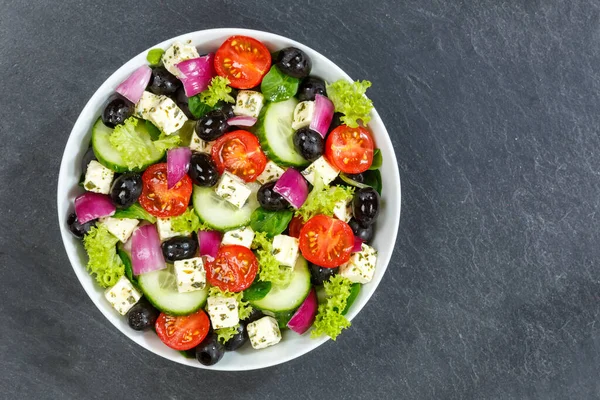新鮮なトマトのオリーブとフェタチーズとギリシャのサラダコピースペースのスレート上から健康的な食べ物を食べる食べる食べる — ストック写真