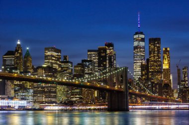 Manhattan 'ın New York şehrinde Brooklyn Köprüsü ve Dünya Ticaret Merkezi gökdeleniyle alacakaranlık gecesi ABD' de
