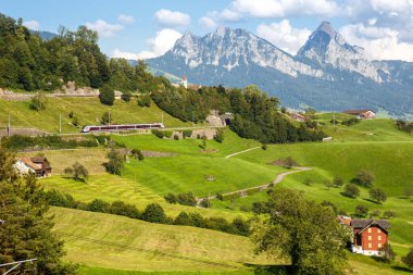 Passenger railway train type Stadler Flirt of Sudostbahn at Grosser Mythen mountain in the Swiss Alps in Arth, Switzerland clipart