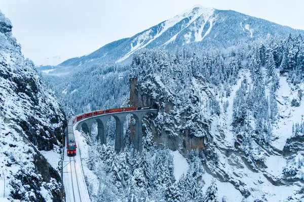 stock image Filisur, Switzerland - January 9, 2024: Rhaetian Railway passenger train at the famous Landwasser Viaduct on Albula line by Stadler Rail in the Swiss Alps in Filisur, Switzerland.