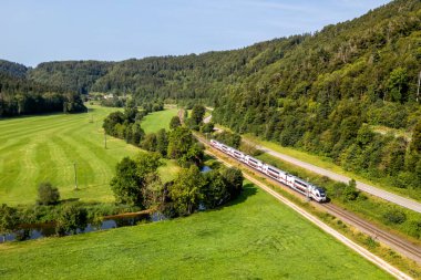 Sulz, Almanya - 23 Ağustos 2024: Almanya 'nın Sulz kentindeki Gaeubahn demiryolu hattında Stadler KISS' den IC2 treni Deutsche Bahn DB 'nin havadan görüntüsü.