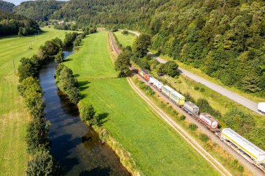 Sulz, Almanya - 23 Ağustos 2024: Almanya 'nın Sulz kentindeki Gaeubahn demiryolu hattındaki Deutsche Bahn DB Cargo yük treninin havadan görünüşü.