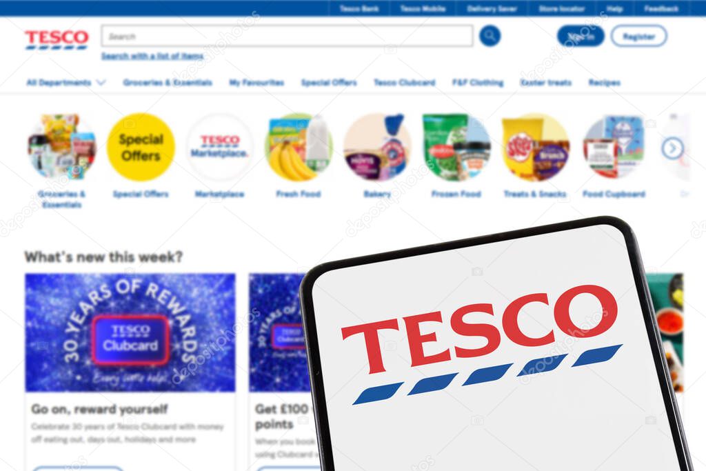 Stuttgart, Germany - February 8, 2025: Tesco supermarket with online shop ecommerce logo on a mobile phone and website in Stuttgart, Germany.