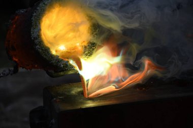 Dökümhanede sıcak beyaz çömlekten sıvı metal dökülüyor. 