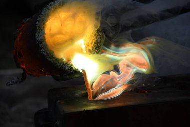 Kızgın alevler ve dumanla birlikte kızgın çömlekten sıvı metal döküyorlar.