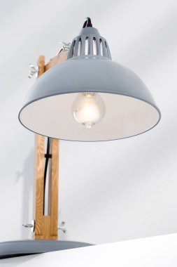  Lambanın gölgesi, ampulün yakın çekimi. Retro ya da antika masa lambası, metal tabanlı ve gri renkli gölgelikli klasik ahşap kol, beyaz arka plana karşı.