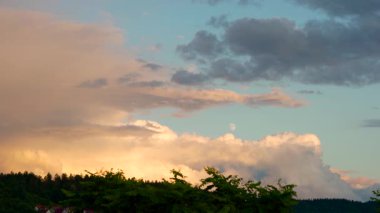 Mavi gökyüzünde görünen ay batarken. Bulutlar tembelce sürükleniyor, rüzgarla savruluyor.