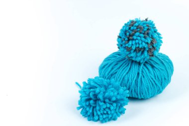 Beyaz arka planda örgü örmek için mavi iplikler. pompon. İplikten yapılmış yumuşacık bir ponpon