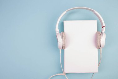 Kulaklık, cep telefonu, idiobook, mavi arka planda kahve fincanı. Boş zaman ve öğrenme kavramı, hobi. Müzik dinlemek, edebiyat. Kopyalama alanı olan üst görünüm