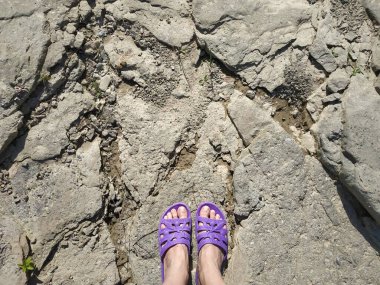 Kadın ayakları parmak arası terlikler, terlikler taşlarda.