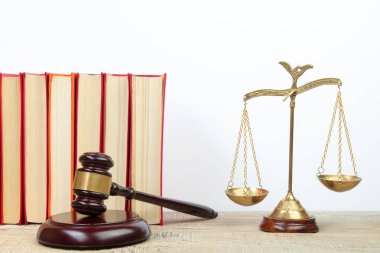 Hukuk konsepti - açık hukuk kitabı, yargıç tokmağı, teraziler, mahkeme salonundaki ya da kolluk kuvvetlerindeki heykel. Tahta masa, beyaz arkaplan.