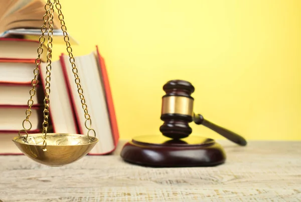Law concept - Open law book, Judge\'s gavel, scales, Themis statue on table in a courtroom or law enforcement office. Wooden table, yellow background.