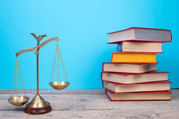 Law concept - Open law book, Judge\'s gavel, scales, Themis statue on table in a courtroom or law enforcement office. Wooden table, blue background.