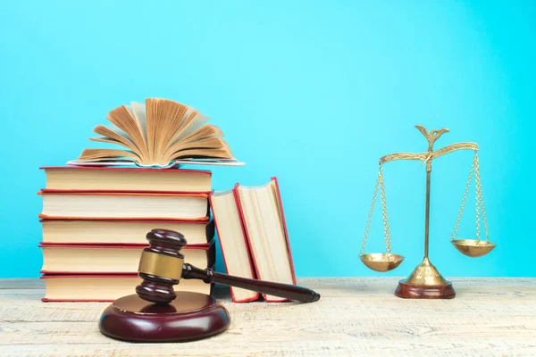 Law concept - Open law book, Judge's gavel, scales, Themis statue on table in a courtroom or law enforcement office. Wooden table, blue background.