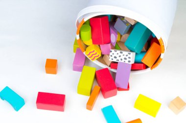 Çocuk oyuncağı, ahşap inşaatçı, beyaz arka planda bir kovadan dökülen